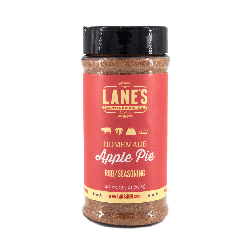 Lane’s Apple Pie Dessert Rub jar beside apple slices, cinnamon sticks, and baked pie.