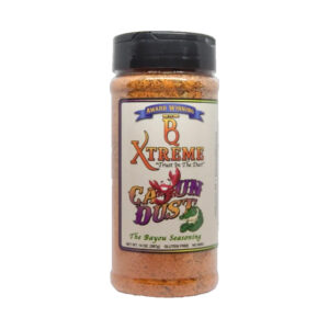 B Xtreme BBQ Cajun Dust bottle surrounded by smoky grilled meats and Cajun spices