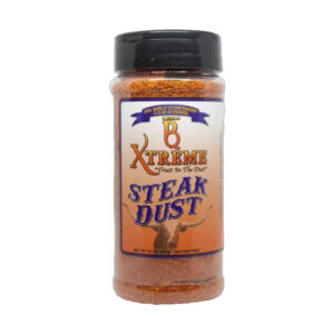 Bottle of B Xtreme BBQ Steak Dust beside grilled ribeye steak and fresh herbs