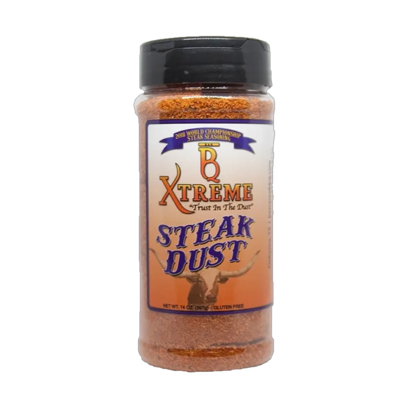 Bottle of B Xtreme BBQ Steak Dust beside grilled ribeye steak and fresh herbs