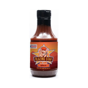 Bottle of Blazing Star Spicy BBQ Sauce beside glazed ribs and grilled chicken