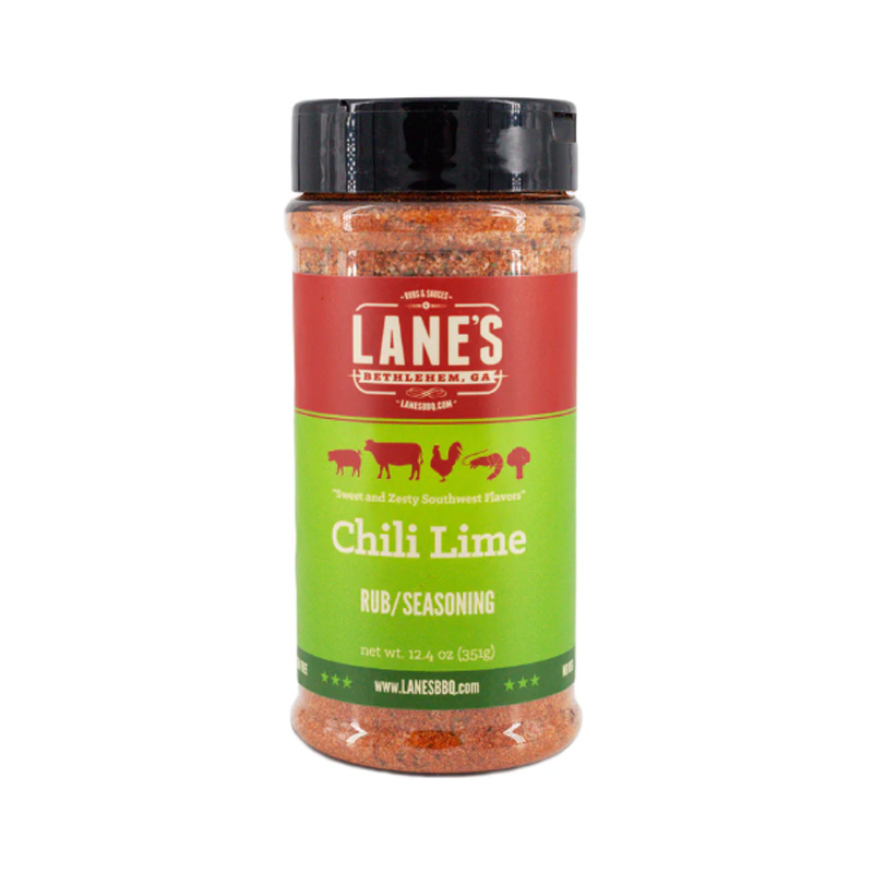 Lane’s Chili Lime Rub jar beside grilled shrimp tacos and lime wedges.