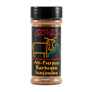 Bottle of Cowtown All-Purpose Barbeque Seasoning beside grilled ribs and chicken