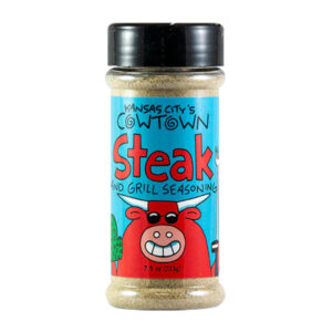 Bottle of Cowtown Steak and Grill Seasoning beside grilled ribeye steak