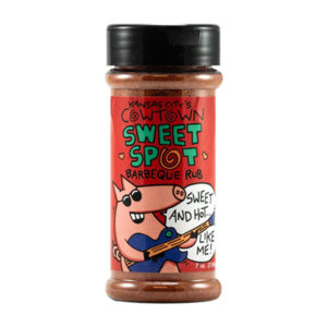 Bottle of Cowtown Sweet Spot rub beside glazed ribs and BBQ chicken
