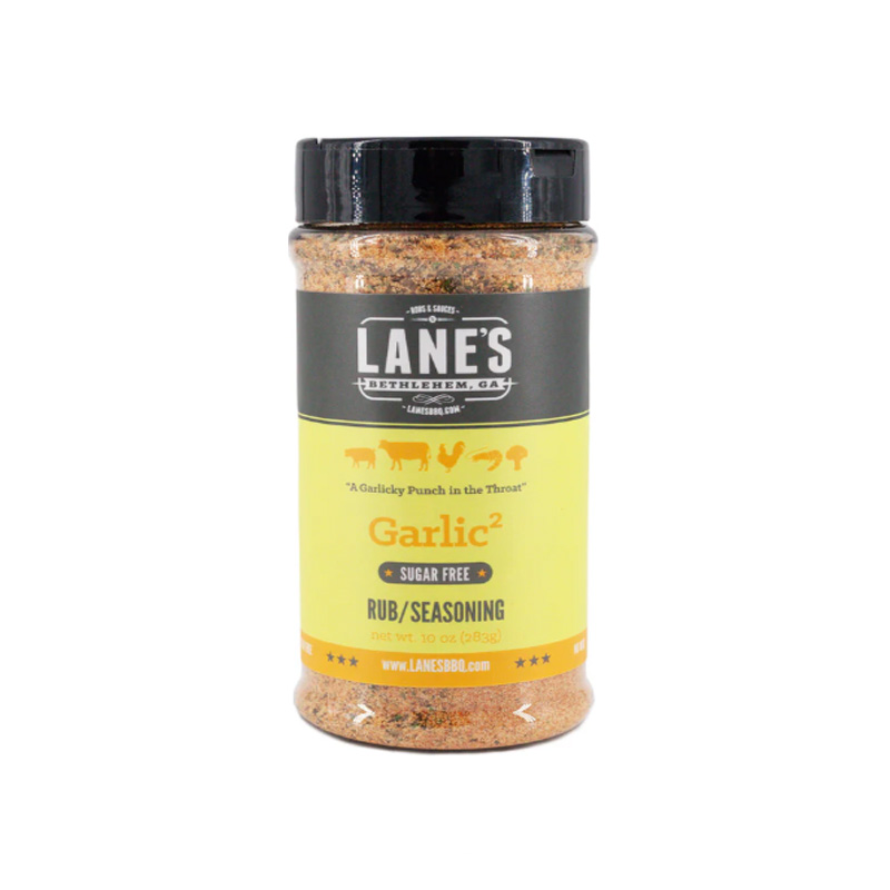 Lane’s Garlic² Rub jar beside roasted chicken and garlic bulbs.