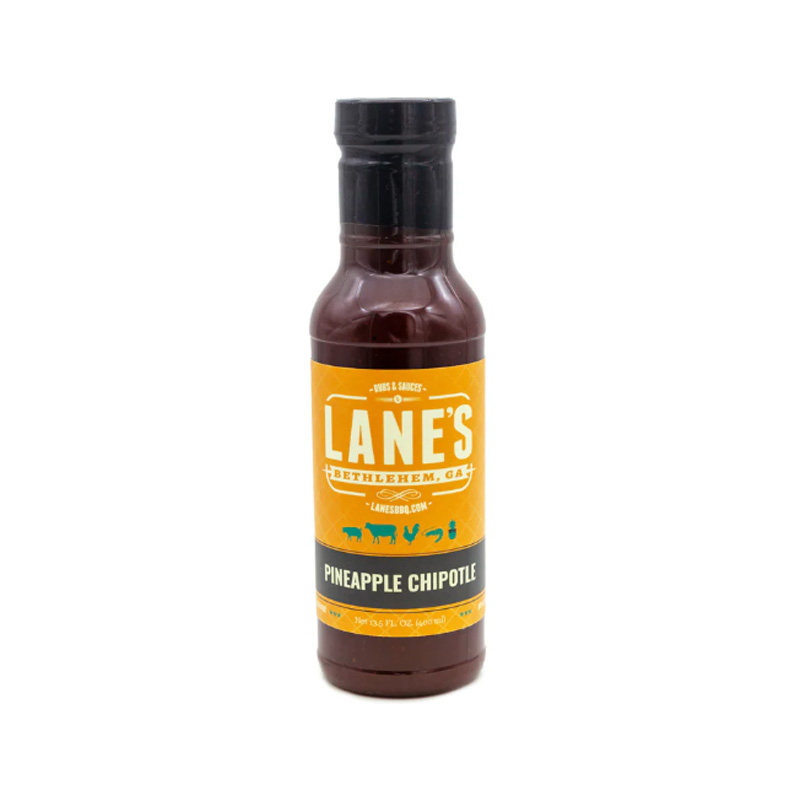 Lane’s Pineapple Chipotle Sauce bottle beside grilled chicken and pineapple slices.