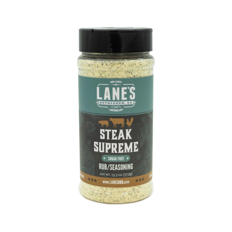 Lane’s Steak Supreme Rub jar beside grilled ribeye steak and herbs.