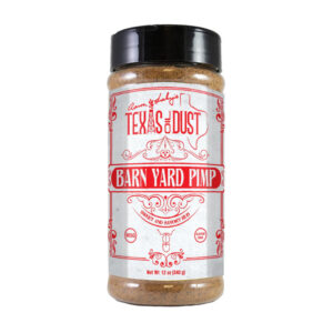 Bottle of Texas Oil Dust Barn Yard Pimp beside grilled chicken and smoked turkey