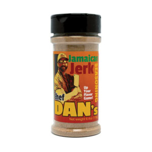 Chef Dan’s Jamaican Jerk Sauce bottle beside grilled jerk chicken and lime wedges.