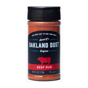Shaker bottle of Oakland Dust Beef Rub beside a grilled ribeye steak with a peppery crust