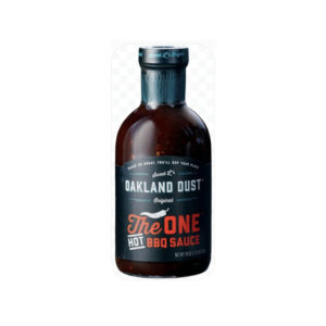 Bottle of Oakland Dust The Hot One BBQ Sauce with ribs glazed in sauce and grill background