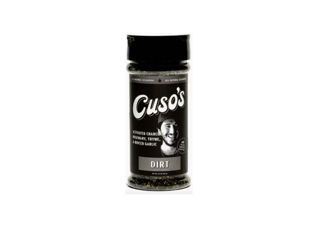 Bottle of Cuso’s Dirt® Seasoning beside a grilled ribeye with blackened crust