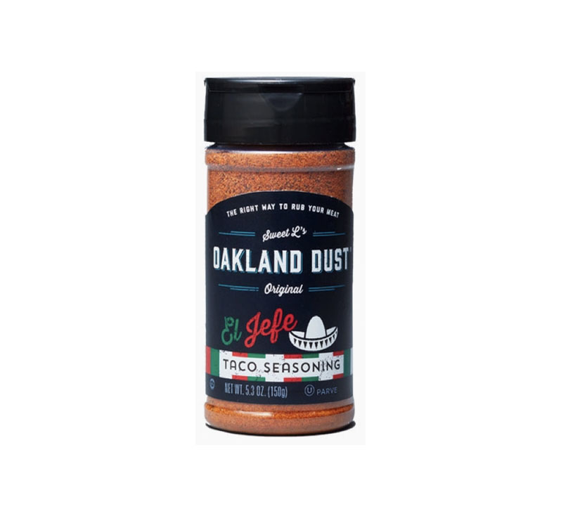 Shaker bottle of Oakland Dust El Jefe Taco Seasoning beside seasoned grilled chicken in taco shells