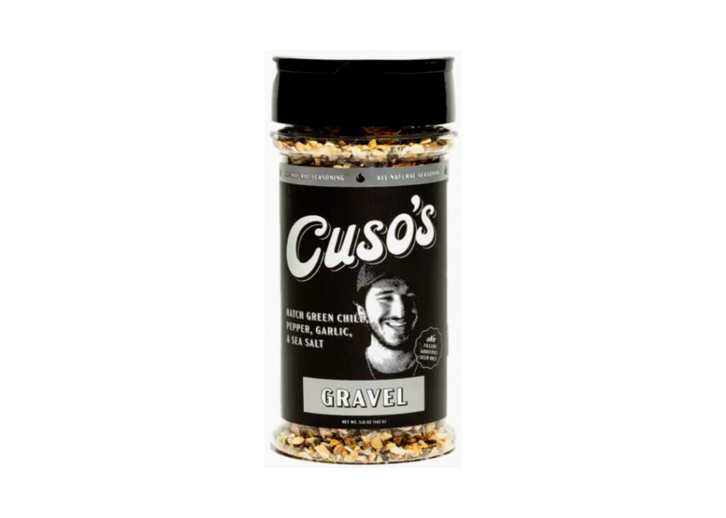 Bottle of Cuso Cuts Gravel Seasoning beside grilled ribeye steak with peppery crust