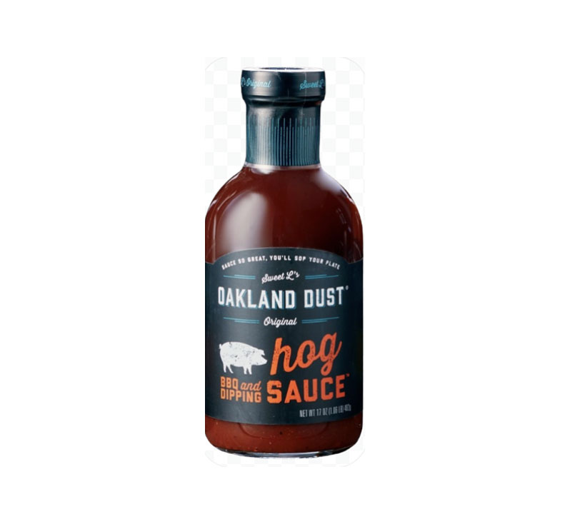 Bottle of Oakland Dust Hog Sauce beside pulled pork sandwich with sauce drizzle