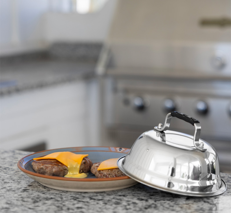 Melted cheese burger beside stainless steel dome