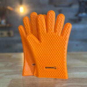 Pair of orange heat resistant silicone gloves on wooden surface